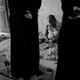 Two women observe Bobby, owner of the Sa-datganj workshop, as he inspects a Mukaish fabric.